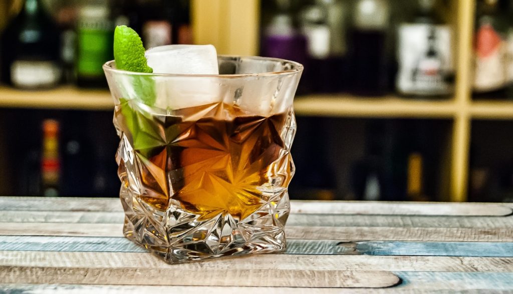 Mixgetränk mit Wein, Eiswürfel und Minzblatt in beschlagenem Whisky-Tumbler 